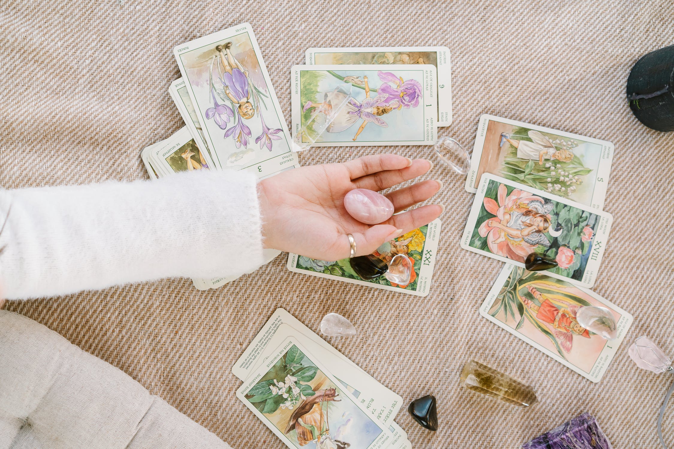Guildance tarot avec des une main qui tient une pierre au dessus des cartes.